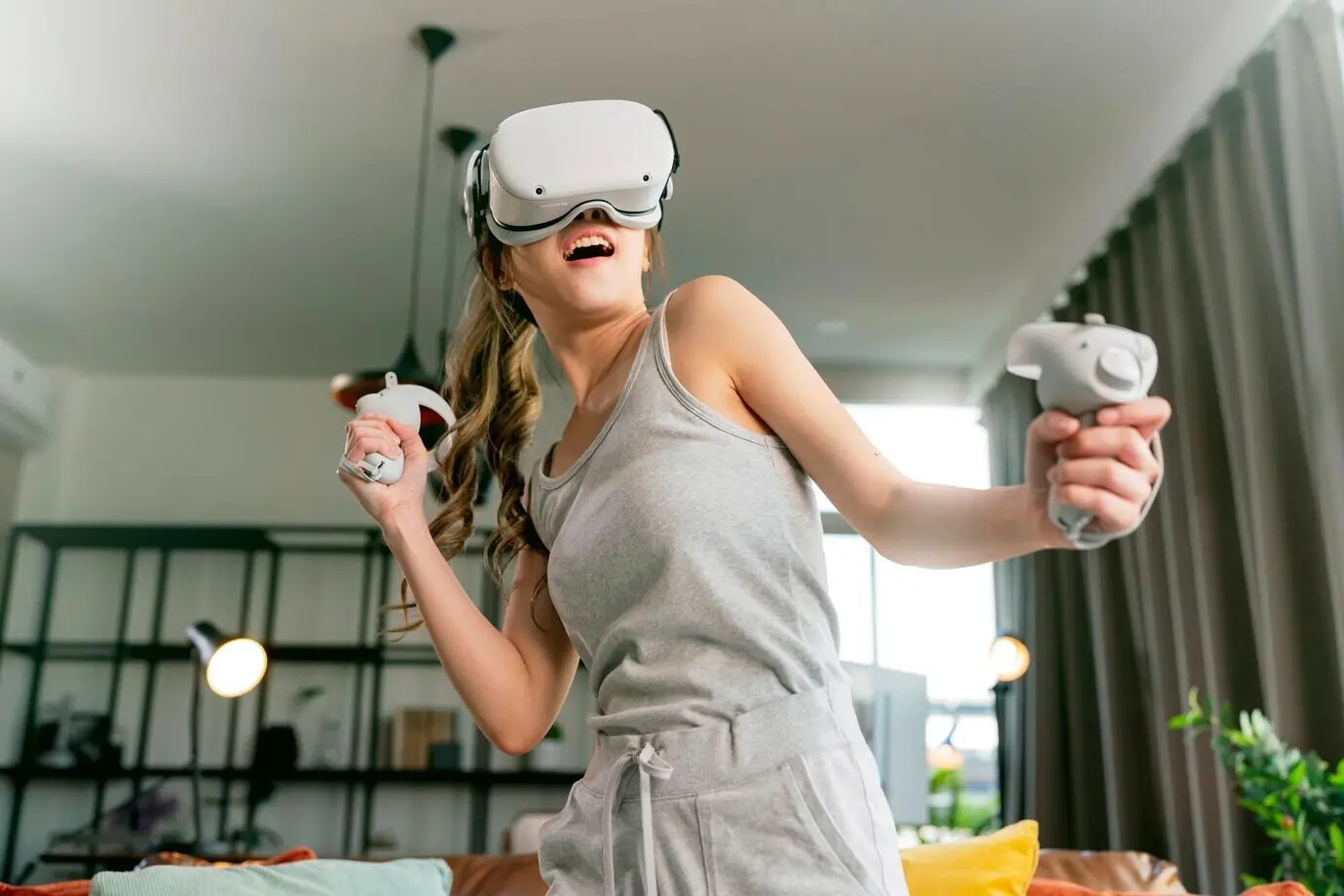 A young Asian woman enjoys a futuristic 3D virtual gaming experience, using VR headset technology to view a simulated digital world and controlling it with hand gestures to beat a fun online virtual game.